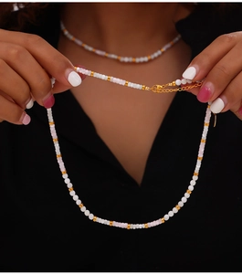 Detail of beaded shell necklace with gold accents and adjustable chain on model