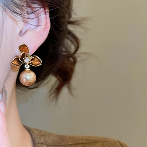 Close-up of amber flower earring with champagne pearl pendant on a female model