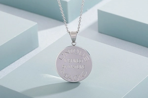 Macro view of silver stainless steel round pendant with UNIQUE and MAGIC engraving
