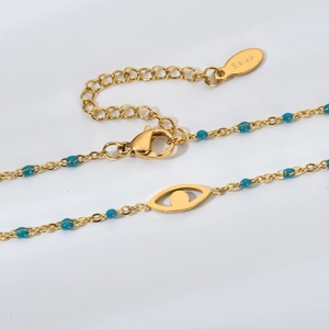 Macro d'un collier doré en acier inoxydable avec perles bleues et pendentif œil