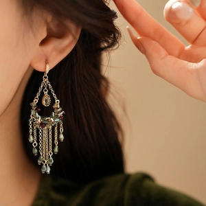 Detail of gold crescent earrings with colorful crystals and long elegant tassels