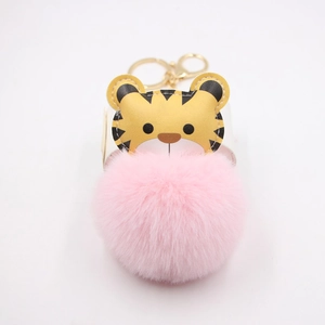 Close-up of pink faux fur ball keychain with yellow cartoon tiger and gold lobster clasp