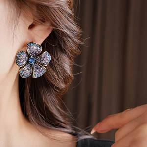 Détail macro d'une boucle d'oreille fleur vintage avec strass violets et bleus