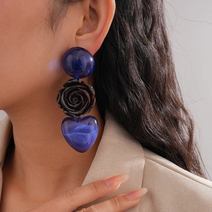 Boucles d'oreilles cœur bleu et rose noire portées par un mannequin, style élégant