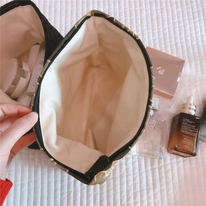 Top view of spacious quilted black makeup bag interior with beige canvas lining