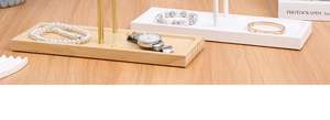 Detail of minimalist white metal jewelry stand with natural rectangular wood base