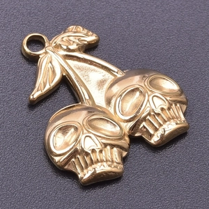 Detailed view of 18k gold plated skull cherry pendant on a textured black background