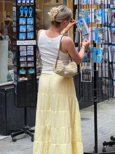 Detail of light yellow tiered maxi skirt showing layered design in a resort style