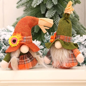 Pair of autumn harvest gnomes with sunflower and berries on snowy pine branch background
