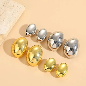 Polished drop-shaped gold and silver earrings in various sizes on a beige stone surface