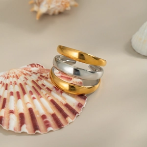 Close-up of three-piece minimalist mixed gold and silver layered open rings on a shell