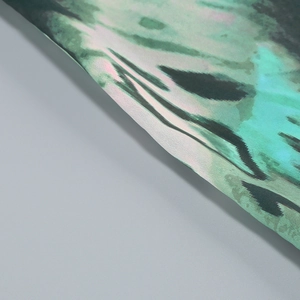 Dettaglio della texture marmorizzata verde e nera sul tessuto satinato di un abito