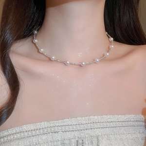 Detail of silver pearl and rhinestone necklace set worn by a model in elegant lighting