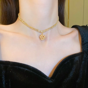 Close-up of golden layered necklace with snowflake pendant and delicate pearls on model