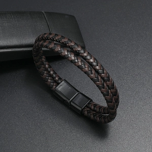 Dettaglio del bracciale in pelle intrecciata nero e marrone con chiusura magnetica in metallo