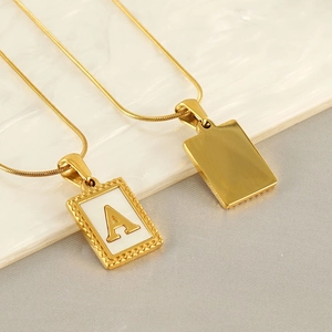Golden snake chain necklaces with letter A pendant and rectangle charm on marble background