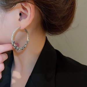 Close-up of geometric hoop earrings with silver needles and micro-set sparkling crystals