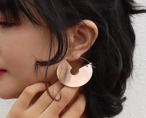 Close-up of model wearing large brushed rose gold flat round hoop earrings in titanium steel
