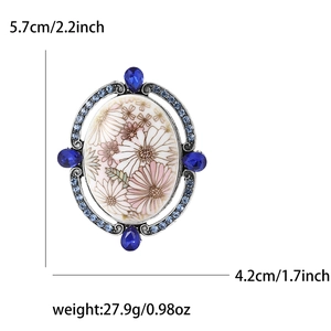 Detailed view of floral enamel brooch with blue crystals and size markings in inches