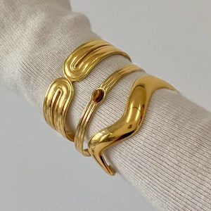 Close-up of gold stainless steel bangle set with brown stone on a model wearing white