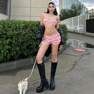 Detail of pink satin two-piece set featuring camisole top and ruffled shorts for summer