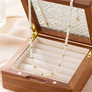 Close-up of elegant white beaded necklace with gold accents on a vintage wooden jewelry box