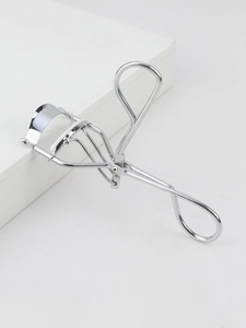 Macro shot of silver stainless steel eyelash curler with white silicone pad on a platform
