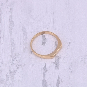 Top view of a gold-plated stainless steel rectangle signet ring on marble background