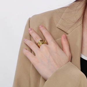 Detail of wide gold textured ring with colorful zircon stones on model's hand