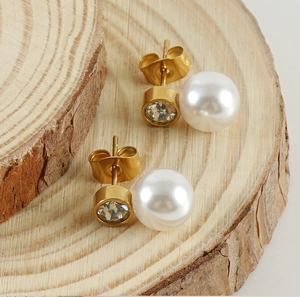 Dettaglio di orecchini a perno con perle e strass placcati oro su base in legno
