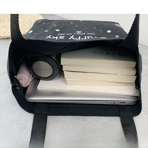 Détail intérieur du cabas en toile noire contenant un ordinateur 14 pouces et accessoires