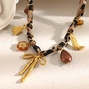 Gros plan du collier plaqué or 18 carats avec tissu léopard et divers pendentifs chic