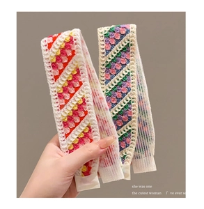 Close-up of handmade knit hairbands with floral patterns and white lace borders
