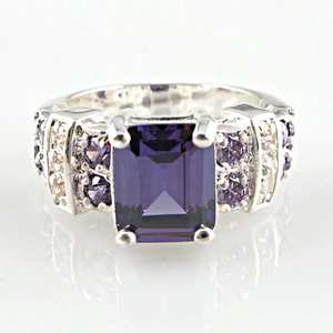 Macro detail of emerald cut purple gemstone ring with ornate micro-pave silver setting