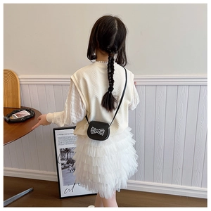 Detail of girl wearing textured knit vest with mesh tutu skirt and bow crossbody bag