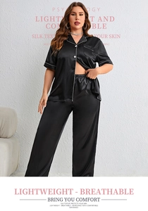 Detail of black silk texture pajama set with white contrast piping and button-down front