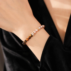 Close-up of tiger eye stone and pearl beaded bracelet worn on a female wrist