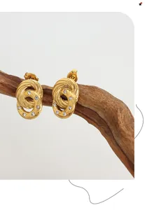 Close-up of vintage gold twisted hoop earrings with zircon stones on a wooden branch