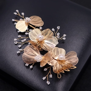 Elegant gold bridal flower headpiece with textured petals and white pearls on black stand