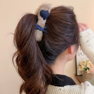 Detail of plush hair claw clip with blue heart decoration shown on a model hairstyle