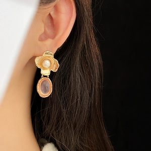 Detail of vintage gold earrings with textured clover pearl and purple oval gemstone