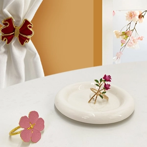 Elegant gold metal napkin rings with painted pink flowers and red rose bud designs