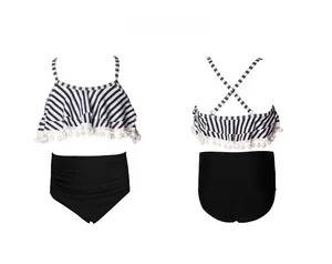 Flat lay of girls' two-piece swimsuit with striped ruffle top and black high-waisted bottom