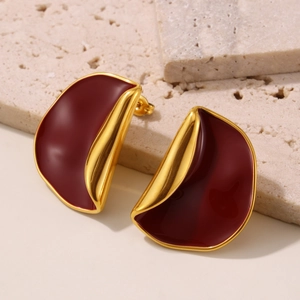Elegant deep red enamel fold earrings with 18k gold plating on stone background