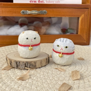 Handcrafted wooden cat figurines with red collars and bells on rustic wood stand