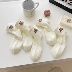 Calze di cotone bianco con ricamo a forma di orso in un ambiente estetico minimalista di stile
