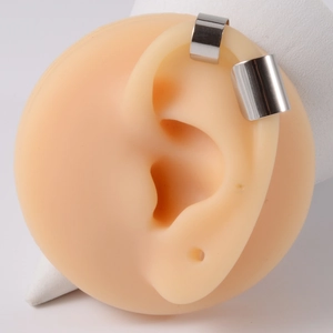 Macro detail of layered silver cuff earrings showing a smooth metallic finish on an ear model