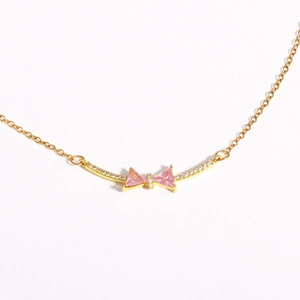 Detail view of a 18K gold-plated necklace featuring a pink zircon butterfly bow pendant