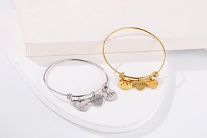 Detail of adjustable heart and MOM charms on gold and silver stainless steel bangles