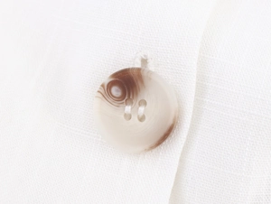 Macro detail of high-quality four-hole resin buttons on a white linen texture jacket